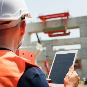Mann auf Baustelle checkt Pläne auf Tablet in der Cloud Computing Software für Braubranche